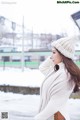 A woman wearing a white sweater and a white hat.