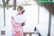 A woman in a pink kimono standing in the snow.