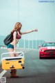 A woman in a bikini holding a cooler on the side of a road.