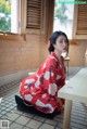 A woman in a red kimono sitting on the floor.