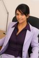 A woman in a purple suit sitting at a desk.