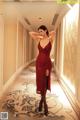 A woman in a red dress standing in a hallway.