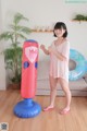 A woman standing next to a giant inflatable punching bag.