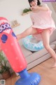 A woman in a pink shirt and red shorts is standing on an inflatable punching bag.