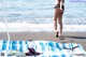 A woman in a bikini standing on a beach next to the ocean.