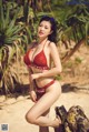 A woman in a red bikini posing on a beach.