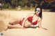 A woman in a red bikini laying on the sand.