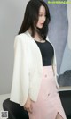 a woman in a white blazer and pink skirt