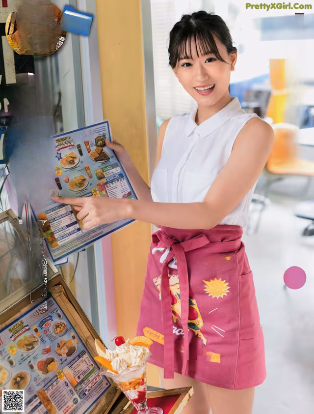 A woman in a pink apron holding a menu.