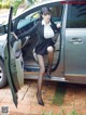 A woman in a business suit is getting out of a car.