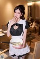 A woman in a maid outfit holding a bowl of food.