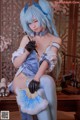 A woman in a blue and white outfit holding a fan.
